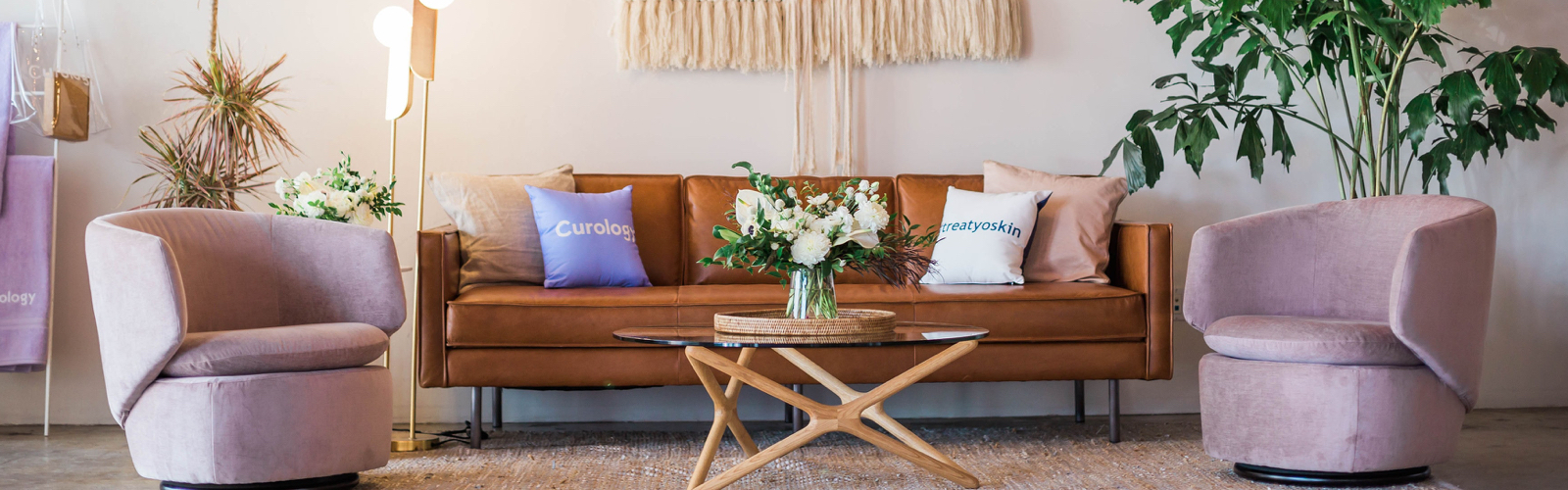 A living room setting with a large brown couch and two pink armchairs